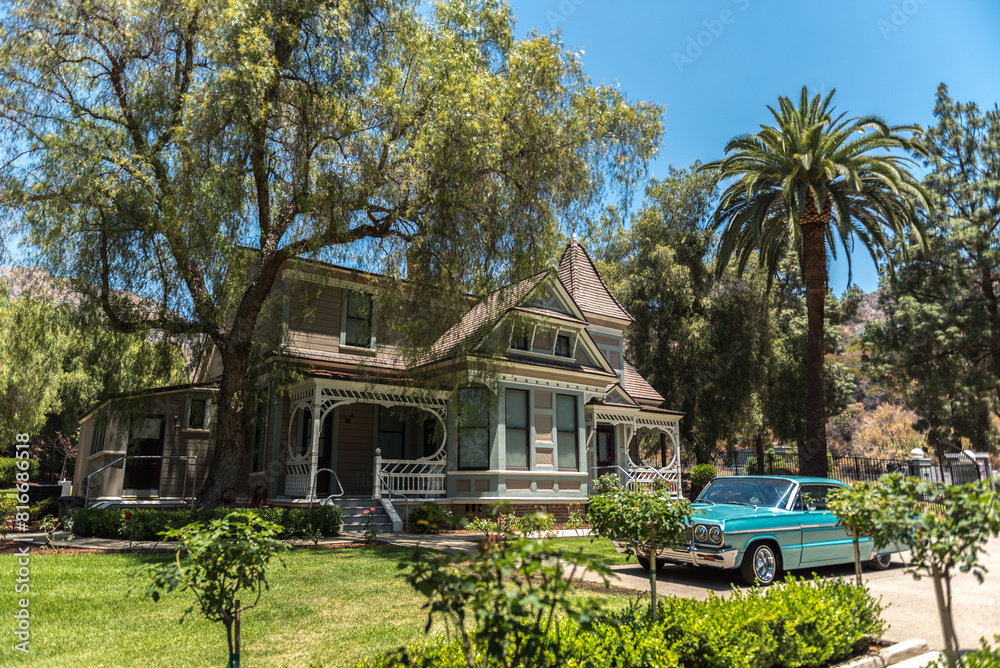 Classic American automobile parked in front of a traditional Victorian style house on a sunny day Classic American automobile parked in front of a traditional Victorian style house on a sunny day