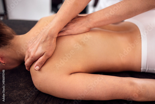 Young caucasian woman getting back massage in spa salon.