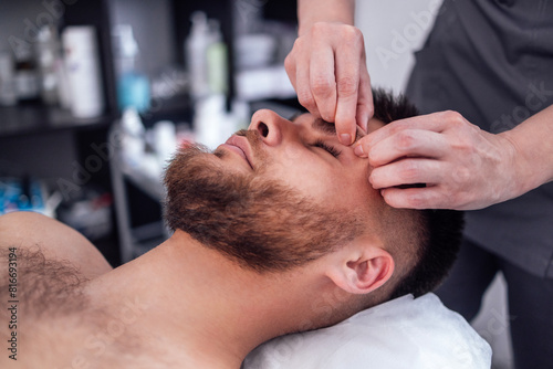 Close up portrait of a young attractive man getting facial massage