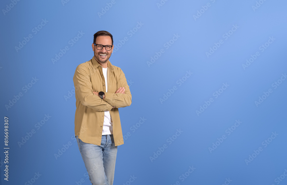 Portrait of confident sales manager with arms crossed smiling and posing on isolated blue background Portrait of confident sales manager with arms crossed smiling and posing on isolated blue background
