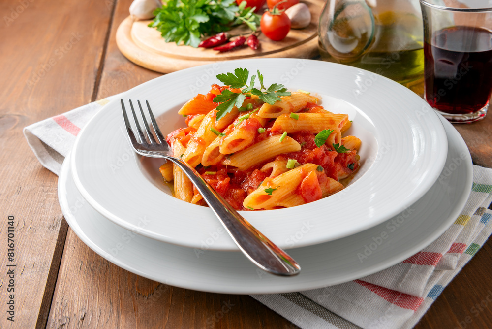 Piatto di deliziose penne all'arrabbiata, tradizionale ricetta di pasta della cucina romana, cibo italiano 