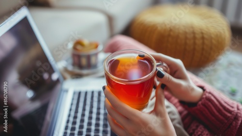 crop young businesswoman using laptop while drinking tea at home