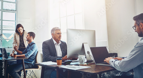 Business people, agency and team with computer in finance, stock market or corporate investment at office. Group of employees, brokers or financial analysts busy or working on technology at workplace