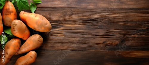 A top view of fresh batata raw sweet potatoes resting on a wooden background on a kitchen table There is plenty of copy space in the image photo