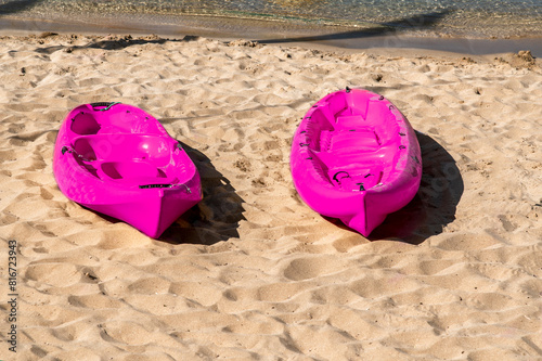 Two pink canoes on the sandy beach