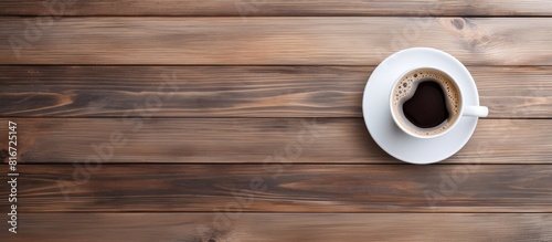 Top view of a white coffee cup on a wooden table with plenty of empty space surrounding the cup for a copy space image