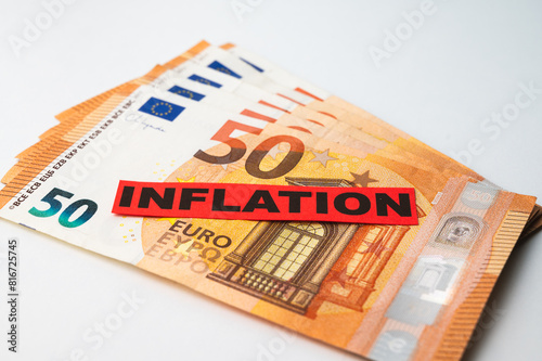 Euro banknotes background, with red ticket with text Inflation.
