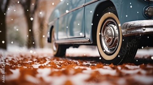 Close-Up of Vintage Car Wheel with Autumn Leaves and Light Snowfall photo