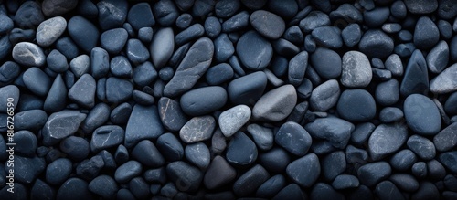 A top down view of a textured background made of dark navy blue stones with an area available for adding an image or text. with copy space image. Place for adding text or design
