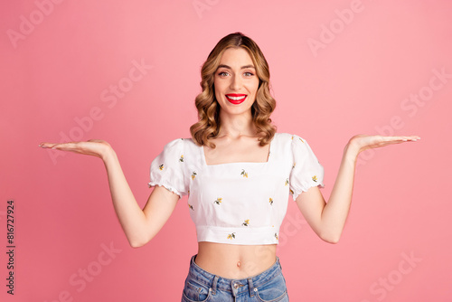 Photo portrait of pretty young girl compare hold empty space wear trendy white outfit hairdo isolated on pink color background