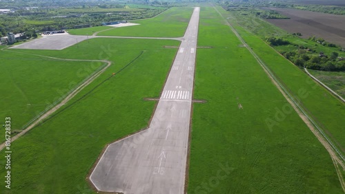 Aerial footage of rural airport runway taxiway and ramp. Airfield tarmac seen from above. Airstrip flyover during a sunny summer day. Instrument landing system on a landing strip. Aerodrome. Bulgaria
