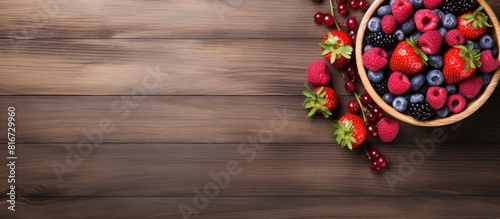 A top down view of a wooden table showcasing a bowl filled with raspberry smoothie and an assortment of berries leaving space to add text or images. with copy space image