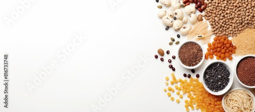 On a white table there is a variety of raw cereals grains pasta and canned food neatly arranged The image includes copy space and is captured in a flat lay style