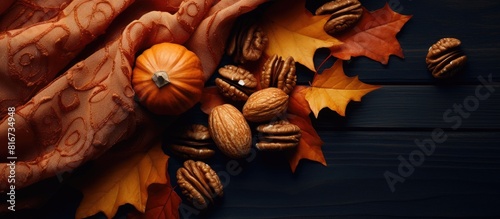 A top down view of a festive autumn pumpkin surrounded by vibrant leaves and walnuts resting on a stylish scarf fabric The image captures the warm glow of sunlight evoking a cozy and cheerful atmosph
