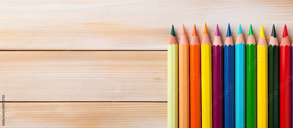On a wooden board there is an empty notebook accompanied by a multicolored pencil The image offers copy space On a wooden board there is an empty notebook accompanied by a multicolored pencil The image offers copy space