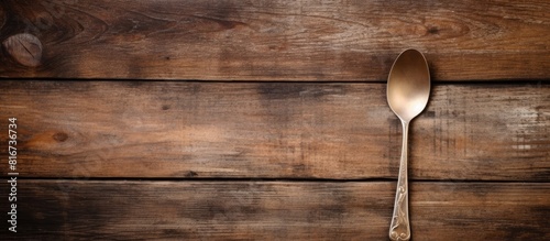 Top view copy space image of vintage spoon and fork resting on an empty weathered cutting board set against an aged wooden backdrop photo