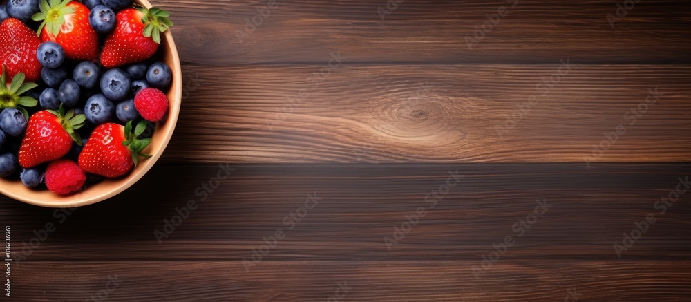 A view from above of a wooden table with a bowl of blueberries and strawberries creating a delightful copy space image A view from above of a wooden table with a bowl of blueberries and strawberries creating a delightful copy space image