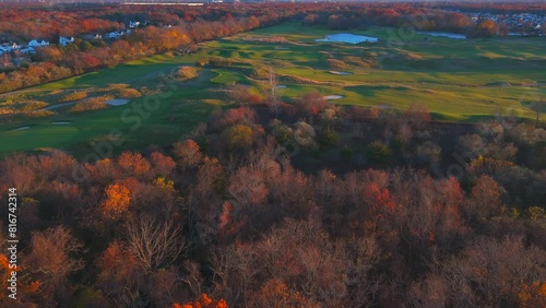 Drone footage of a grassy field with ponds and fall trees in Central Islip hamlet at sunset, USA photo