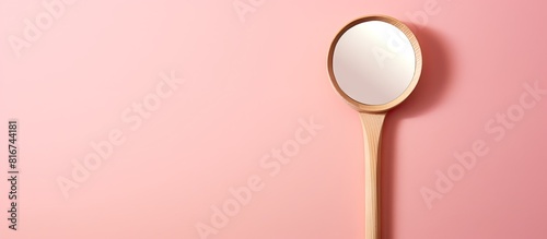 A wooden toy dental inspection mirror for examining teeth placed on a pink background with a prominent shadow This copy space image represents the concept of dental health and highlights the reflectio photo