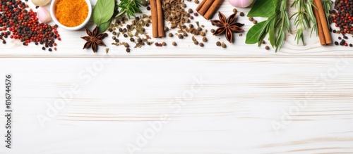 A top down view of spices and fresh herbs arranged on a white wooden surface creating a copy space image for adding text