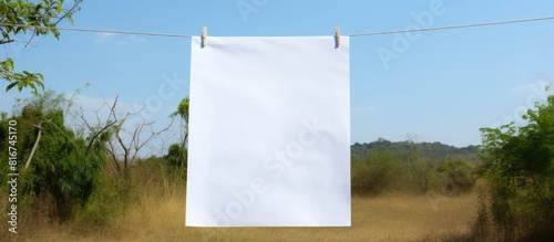 A white paper sheet hangs on a clothesline creating a copy space image photo
