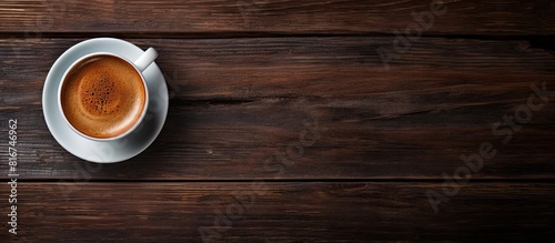 A top down view of a cup of espresso on a dark wooden background with a free area for text creating a copy space image