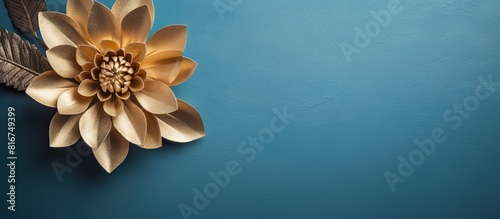 A stunning gold Christmas flower sits on a vintage blue background in this flat lay design providing ample copy space It is horizontally oriented