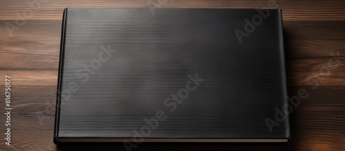 A black book is seen placed on a wooden surface providing ample space for copy or additional images