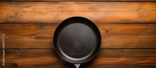 A copy space image of a black frying pan sits on a wooden background appearing empty and ready for use