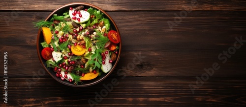 On a dark wooden background there is a top view of a vegetarian salad The salad mix includes cucumber dill croutons cheddar cheese corn pomegranate and chia seeds all drizzled with olive oil Copy spa