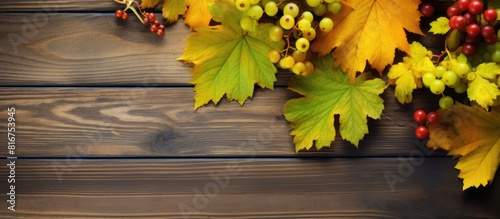 A captivating autumn composition featuring vibrant yellow and green leaves along with mountain ash berries exudes juicy and bright colors on aged wooden boards creating an irresistibly alluring and t photo
