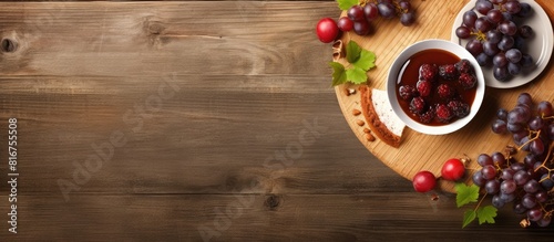 Top view of a holiday cake accompanied by a cup of coffee and grapes all placed on a light wooden background There is ample copy space available for additional elements