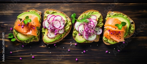 Sandwiches or toasts with salted salmon avocado guacamole red onions and basil on old red wooden background Set of danish open sandwiches Healthy food breakfast Dieting food concept Top view