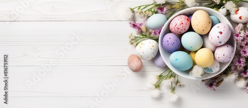 Easter greeting card with colorful eggs in bowl on white wooden table Top view with space for your greetings Image. copy space available