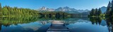 A tranquil mountain lake reflecting surrounding pine trees and peaks, wooden dock in the foreground, clear sky, wideangle shot