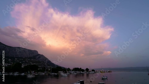 Time-lapse shot of sunsetting in small harbour in middle-terrain country. Summer view of many small boats in port.