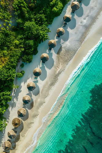 Aerial view of exotic beach with turquoise water and sun parasols. Summer seascape with sun umbrellas on white sand. Travel and exotic holidays concept.
