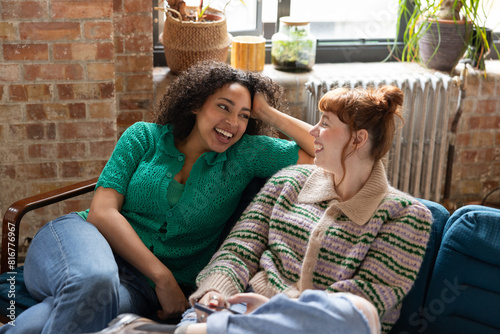 Two young adult friends laughing together in a shared loft apartment photo