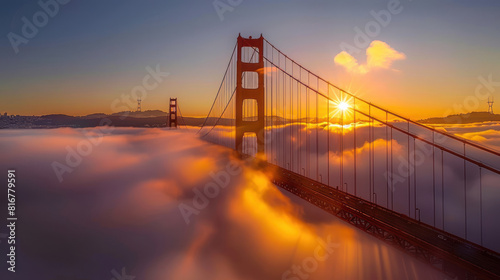 The sun rises behind the fog-covered Golden Gate Bridge, casting a warm, golden glow over the misty landscape as the city awakens to a new day. 