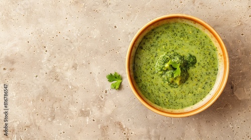 Creamy broccoli and spinach soup in a bowl on a light brown granite surface top down shot with room for text