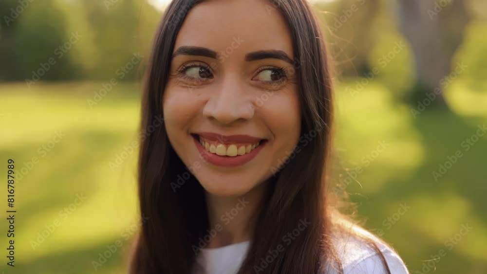 Portrait of an attractive brunette woman walking in the park at spring on a sunny day and smiling. The face of a happy beautiful woman outdoor. Slow-motion 4k footage Portrait of an attractive brunette woman walking in the park at spring on a sunny day and smiling. The face of a happy beautiful woman outdoor. Slow-motion 4k footage