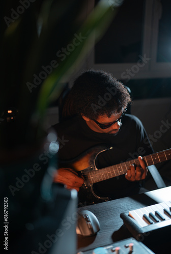 young black african blind musician with glasses playing guitar in production studio