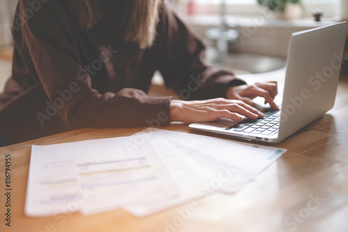 hands of woman using laptop, reading letter savings employment tax paying energy bill 