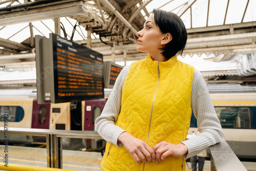 worried Woman looking departure board waiting for train at  train station. Travel lifestyle concept.