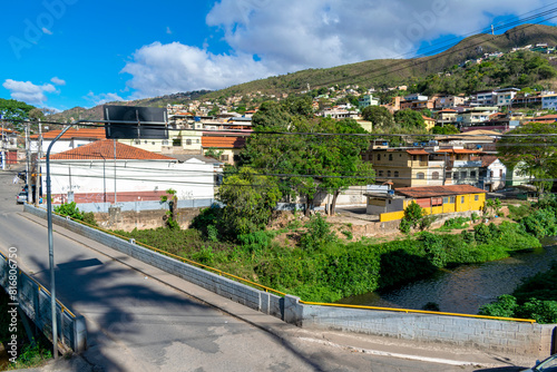 Partial view of the city of Sabará, Brazil. Streets, bridge, mountain, trees and blue sky with clouds.