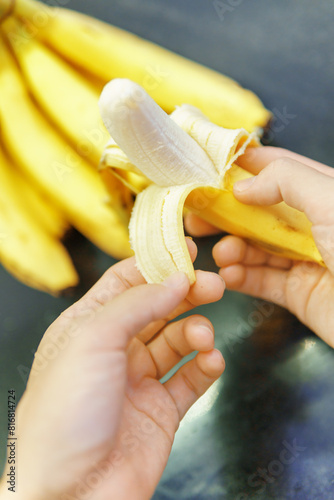 Woman hands peeling fresh banana in a kitchen. Ripe fruit