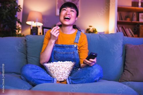 Woman switching channals using remote control while watching TV at home late at night photo