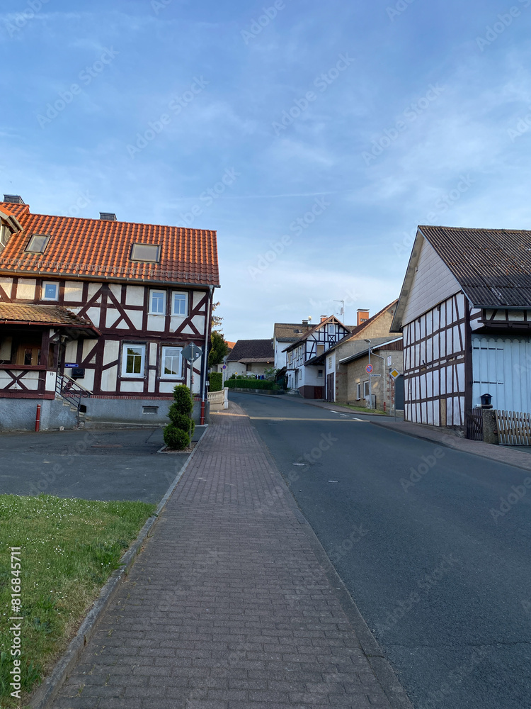 A charming street in a peaceful village with traditional half-timbered houses and a clear blue sky. Tranquil rural scenery