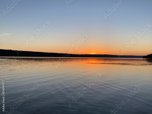 Beautiful sunset over a calm lake with gentle ripples and vibrant colors in the sky. A serene and picturesque water landscape