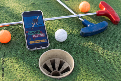 golf equipment on the green lawn. mini golf sports betting on a smartphone